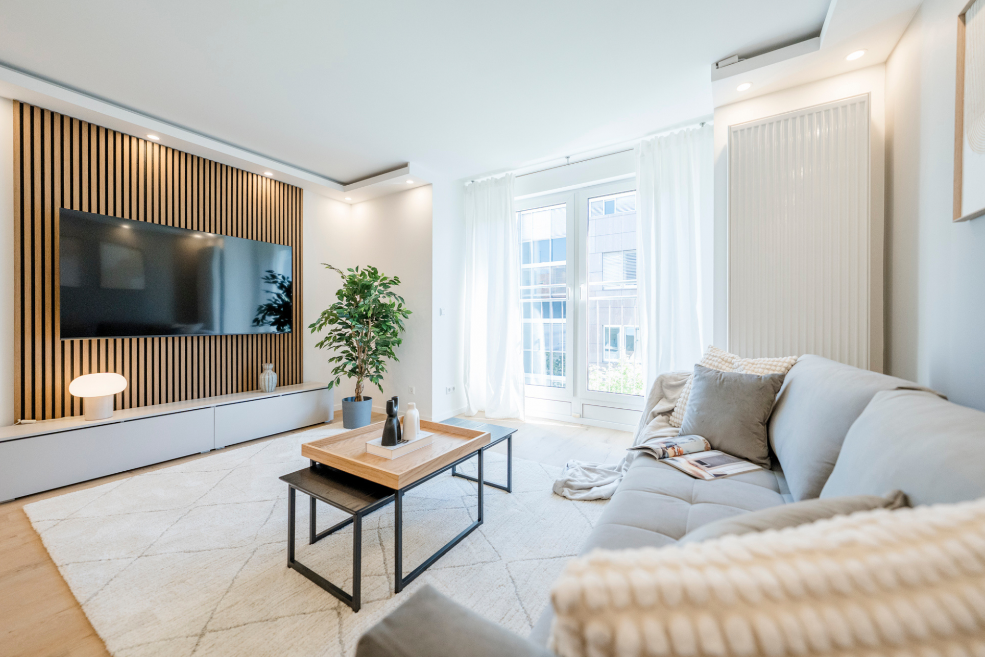 Heller Wohnbereich eines möblierten Apartments in Stuttgart mit Sofa, Couchtisch, großem Fenster und moderner Einrichtung